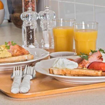 Two identical breakfast plates served on a light wooden tray in a kitchen.