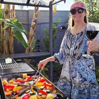 smiling-woman-with-a-pink-cap-and-sunglasses-is-cooking-colourful-vegetables